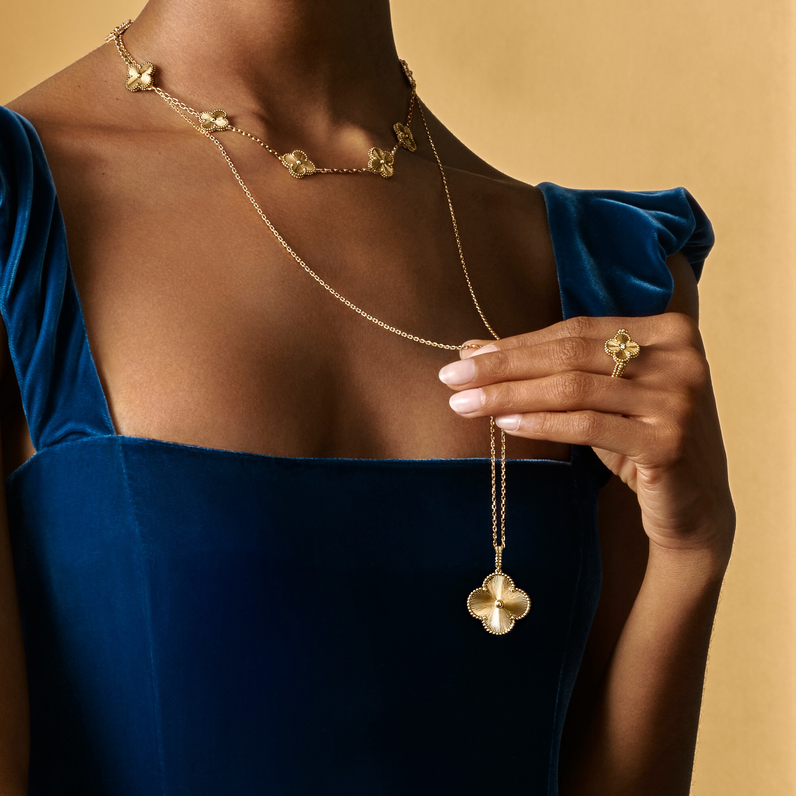 Vintage Alhambra® reversible ring, guilloché 18k yellow gold, blue agate, diamond, Vintage Alhambra® 10 motifs necklace and earrings, guilloché 18K yellow gold. Magic Alhambra® long necklace, 1 motif, guilloché 18K yellow gold. Alhambra® collection, Van Cleef & Arpels.